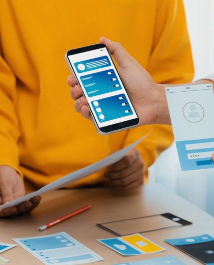 Panorama banner of startup company employee planning on user interface. Synergic Panorama banner of startup UX developer or company employee design user interface or UI prototype for mobile application or website software with software display on smartphone in office. Synergic